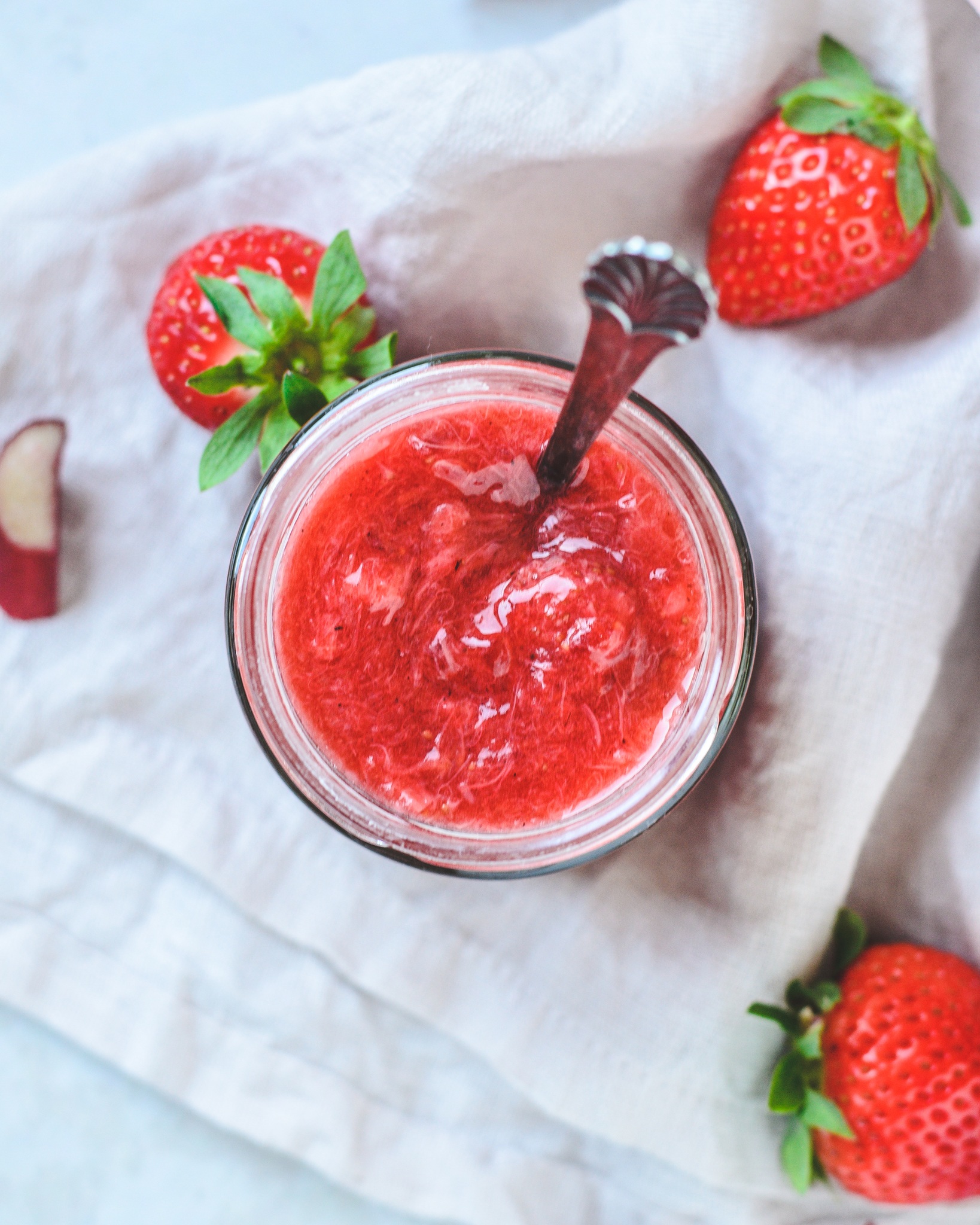 Hjemmelavet jordbær rabarber marmelade i glas med sløjfe om.