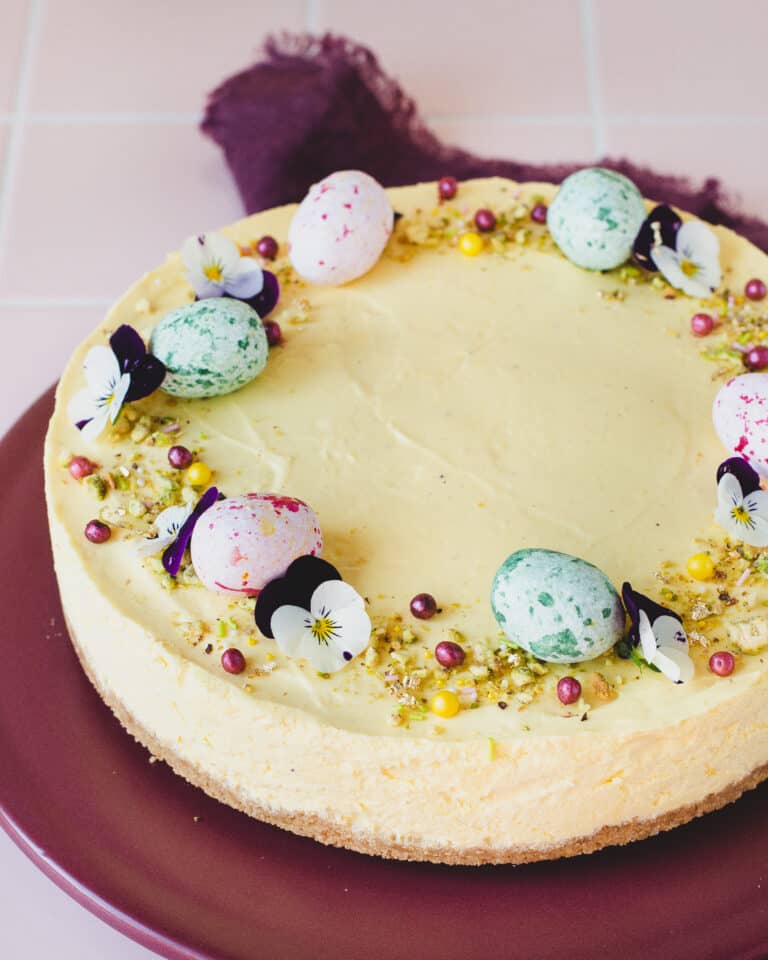 Lækker påskecheesecake med citron og hvid chokolade. Pyntte med lyserøde og grønne marcipan æg, blomster og chokoladekugler.