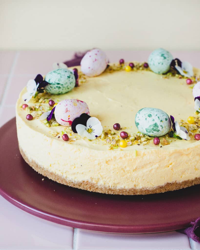 Lækker påskecheesecake med citron og hvid chokolade. Pyntte med lyserøde og grønne marcipan æg, blomster og chokoladekugler.
