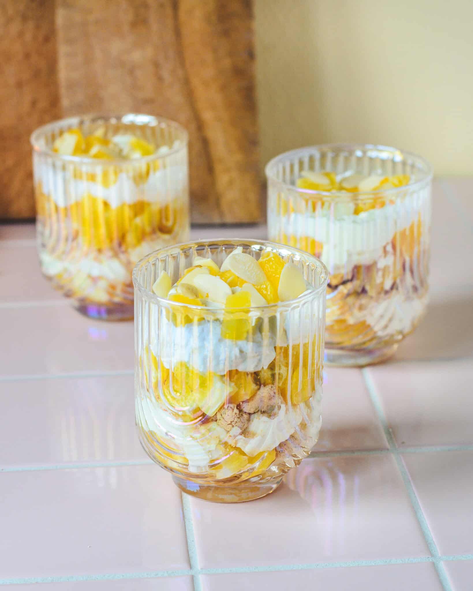 Tre glas med hjemmelavet appelsintrifli i lag – mascarpone, appelsin, makroner og mandelflager. En frisk og enkel dessert til både hverdag og fest.