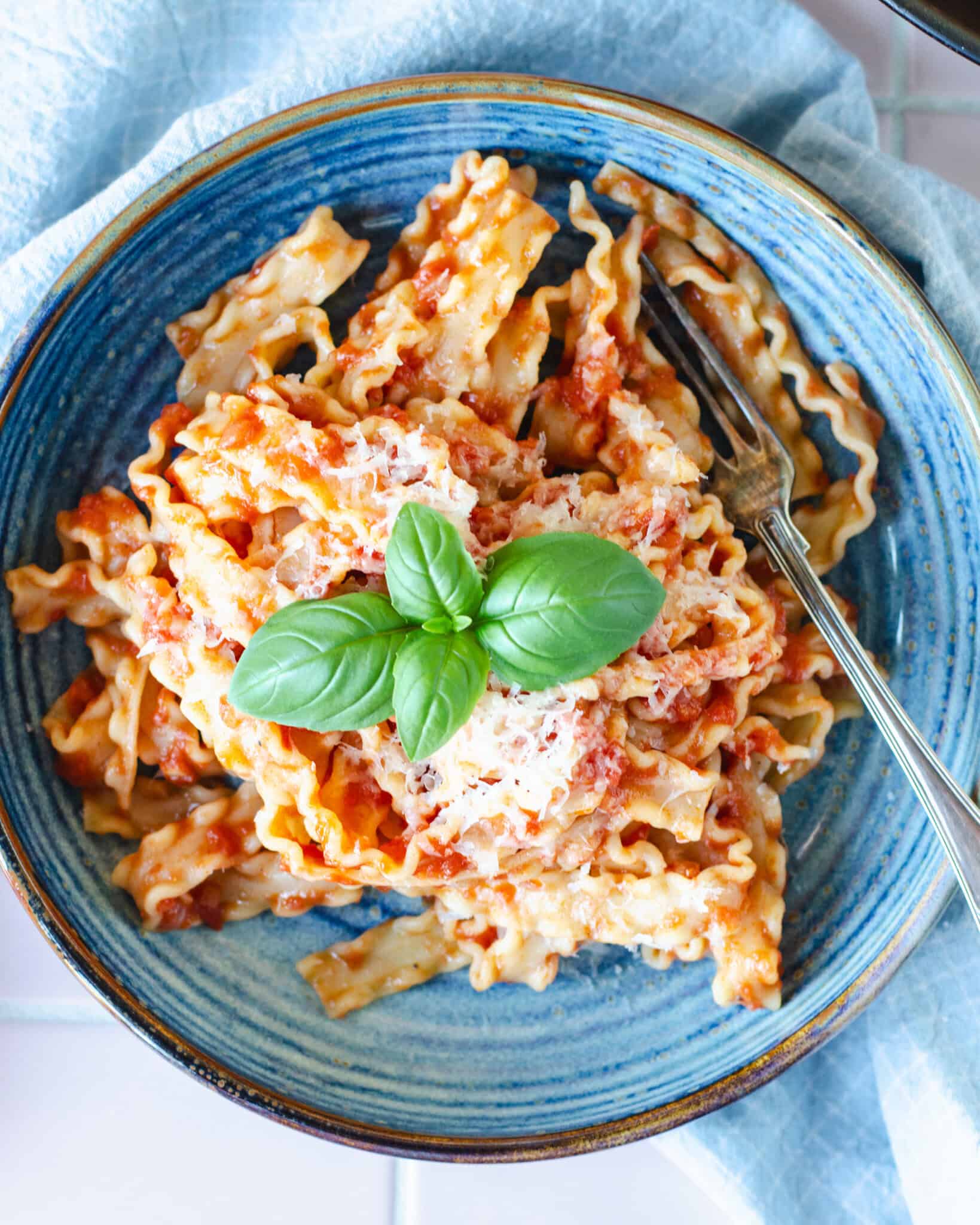 Lækker pasta pomodoro - pasta med tomatsovs toppet med revet parmesan og frisk basilikum, serveret i smuk blå skål