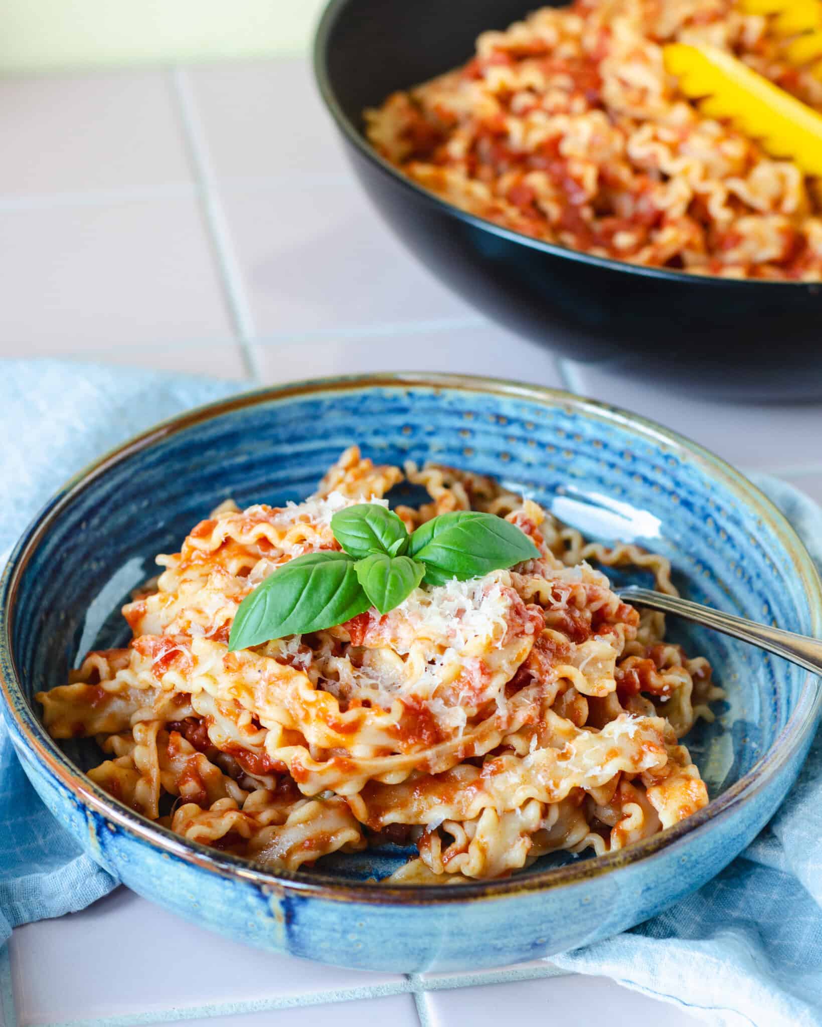 Lækker pasta pomodoro - pasta med tomatsovs toppet med revet parmesan og frisk basilikum, serveret i smuk blå skål