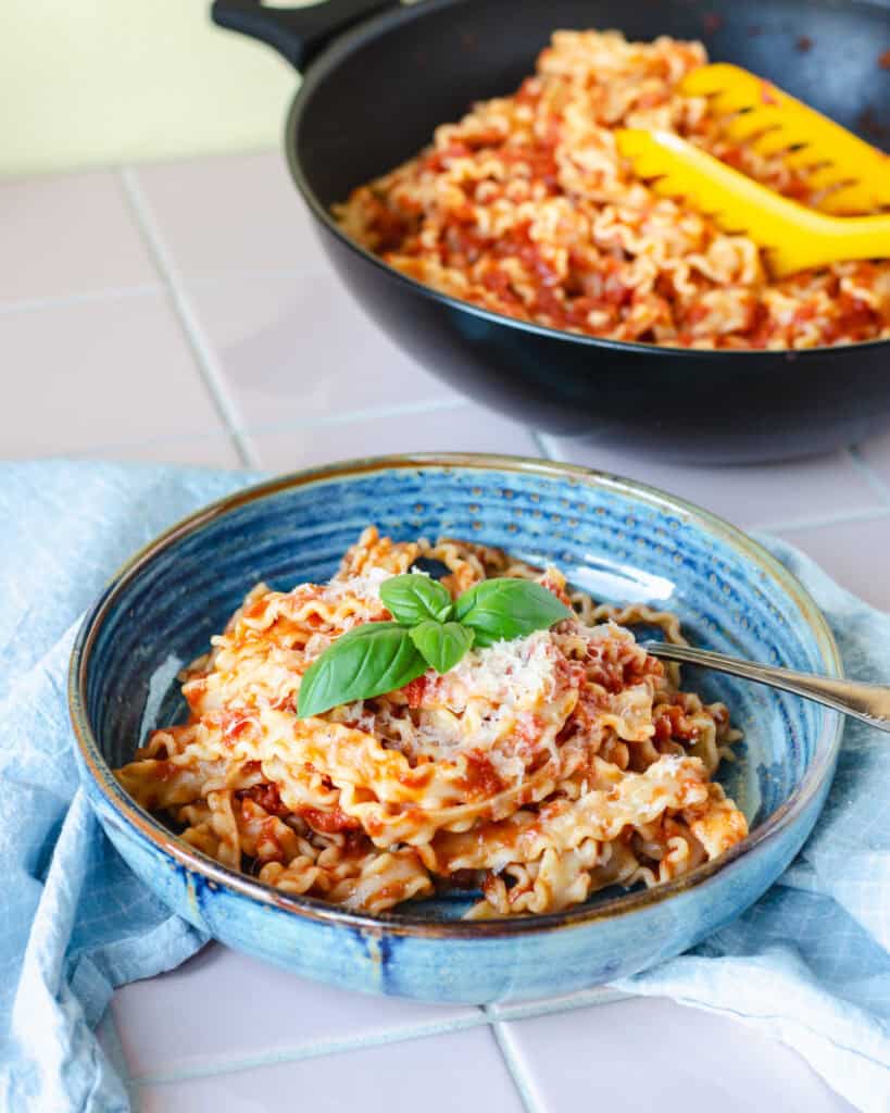Lækker pasta pomodoro - pasta med tomatsovs toppet med revet parmesan og frisk basilikum, serveret i smuk blå skål