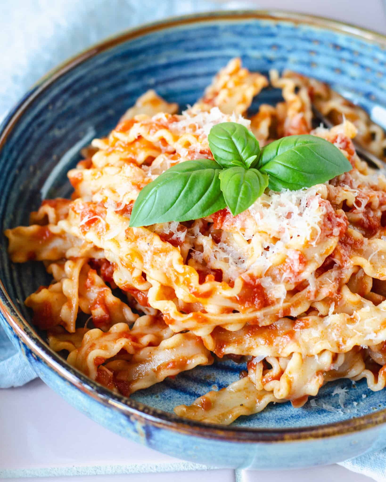 Lækker pasta pomodoro - pasta med tomatsovs toppet med revet parmesan og frisk basilikum, serveret i smuk blå skål