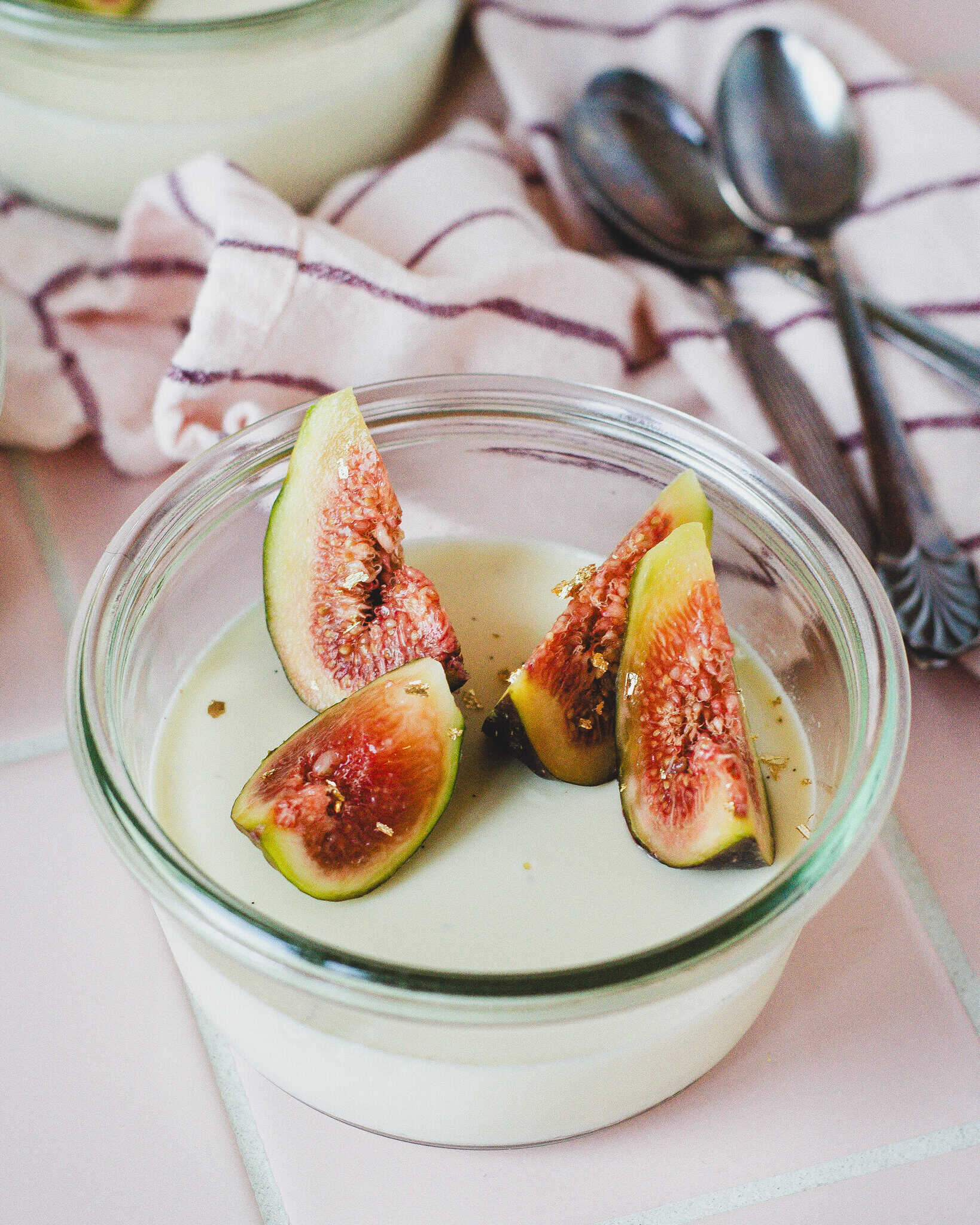 Glas med panna cotta med figenblade og friske figner på toppen – nem dessertopskrift med elegant smag.