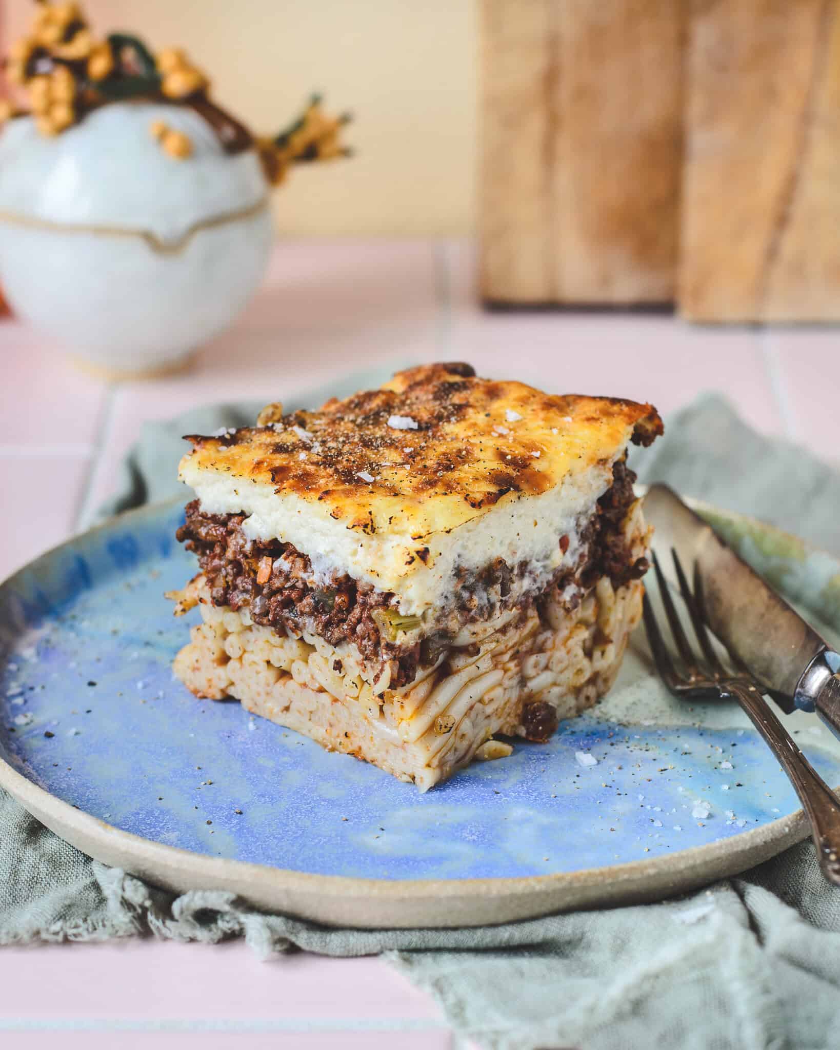 Portionsstykke pastitsio på tallerken. Græsk lasagne i tre lag med pasta, kødsovs og bechamel – nem og smagfuld opskrift på pastitsio.